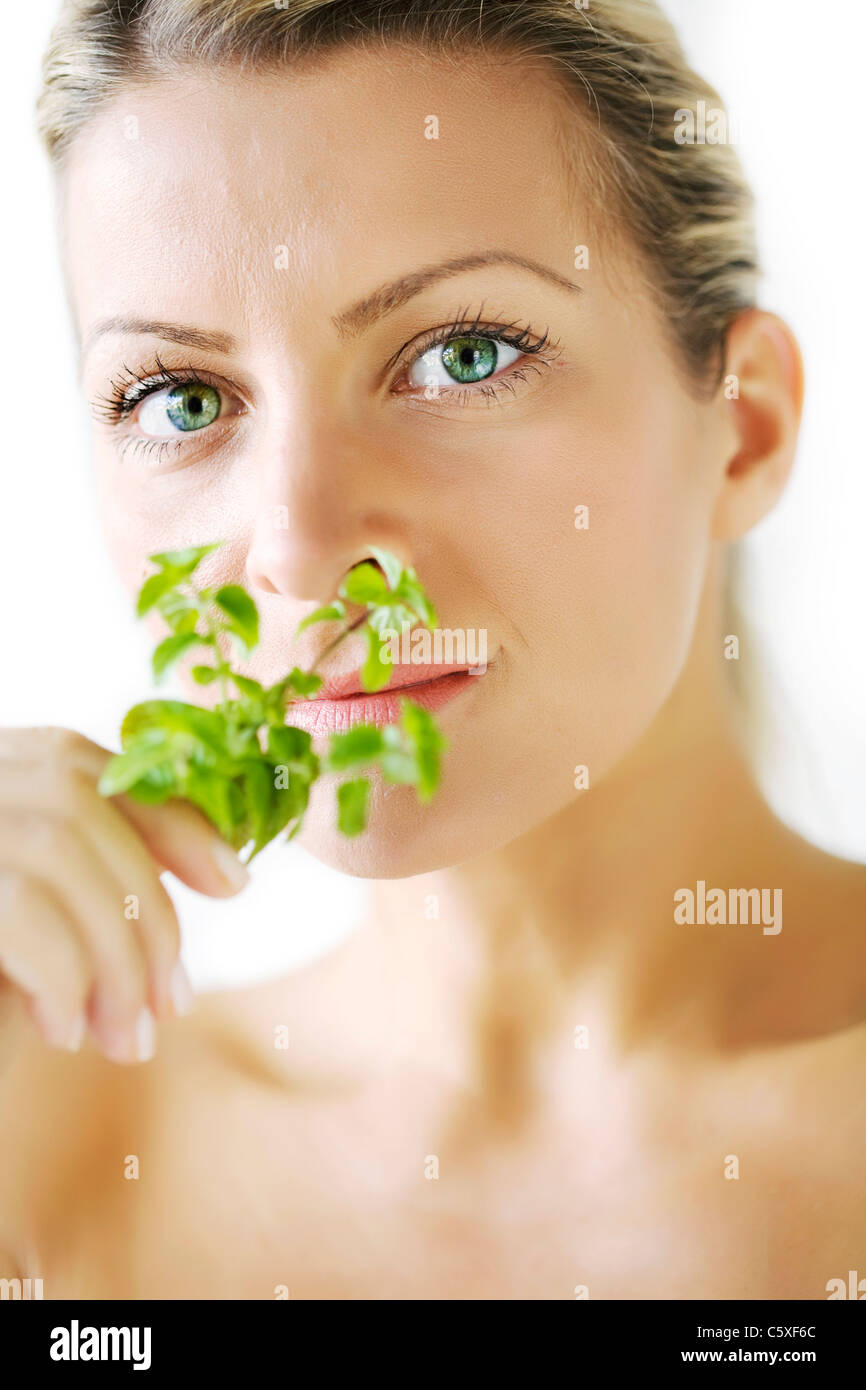 female smelling mint branch, focus is on the eyes, not on the plant Stock Photo