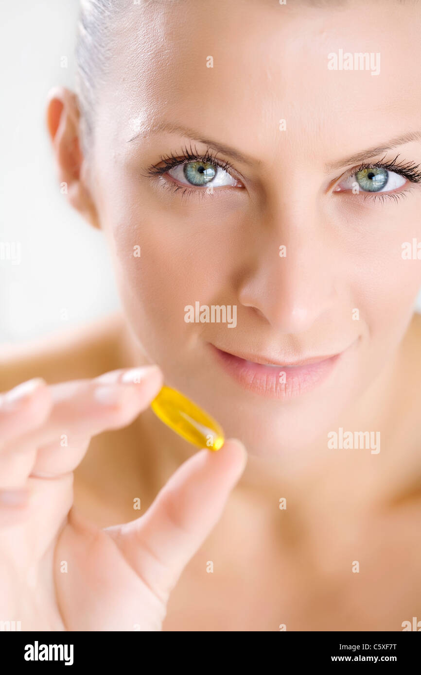 woman holding gelatine capsule, focus is on the eyes Stock Photo