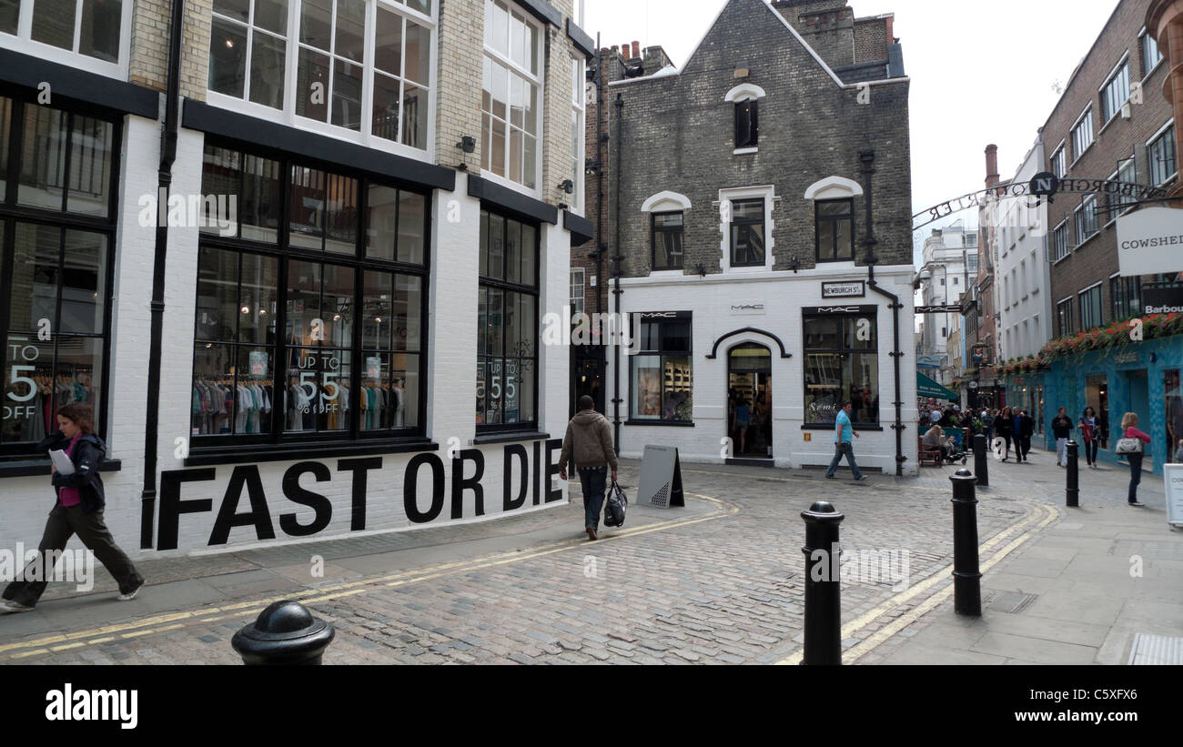 Pedestrians on cobbled stone street walking past 55DSL boutique on Newburgh Street and Foubert Place near Carnaby Street London Stock Photo