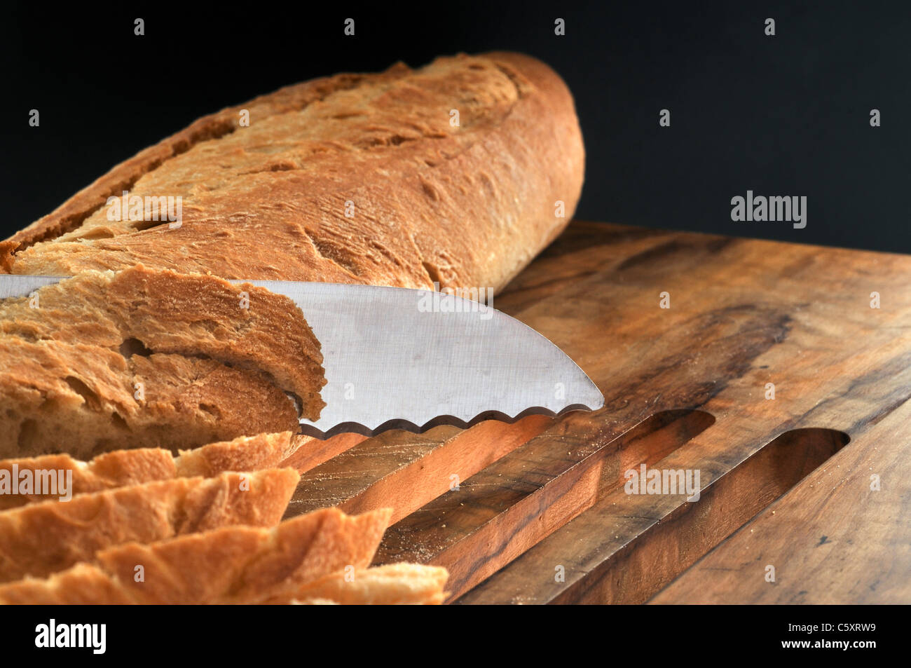 Cutting slices from bread loaf Stock Photo