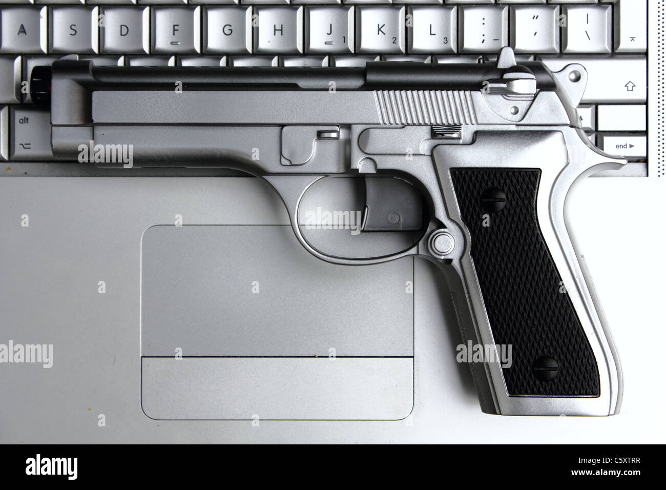 a silver gun on a Macbook pro laptop , conceptual image , metaphor