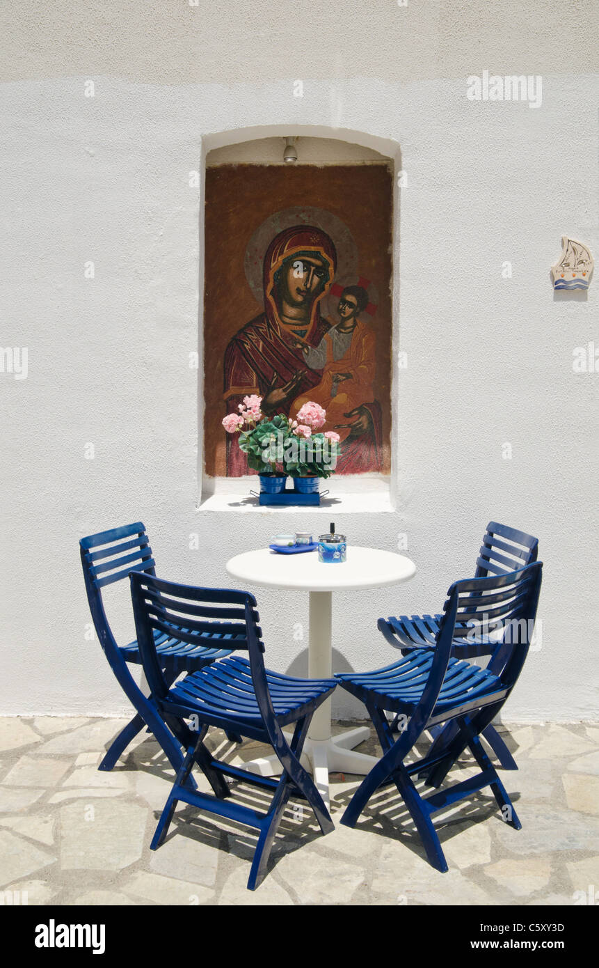 Table and chairs under a religious alcove mural in Nisyros, Greece Stock Photo Alamy
