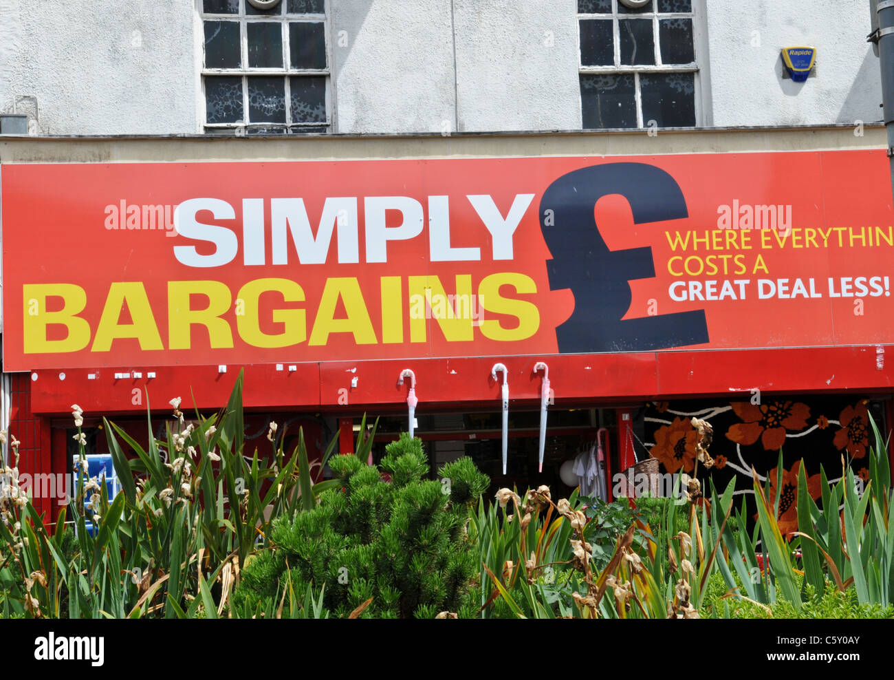 Large red tatty  shop sign saying Simply Bargains on a run down building in West Bromwich High Street Stock Photo