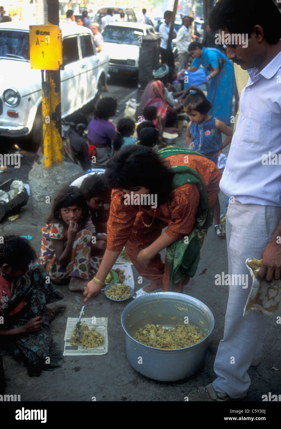 Hindu woman distributing rice to poor people in Mumbai Stock Photo
