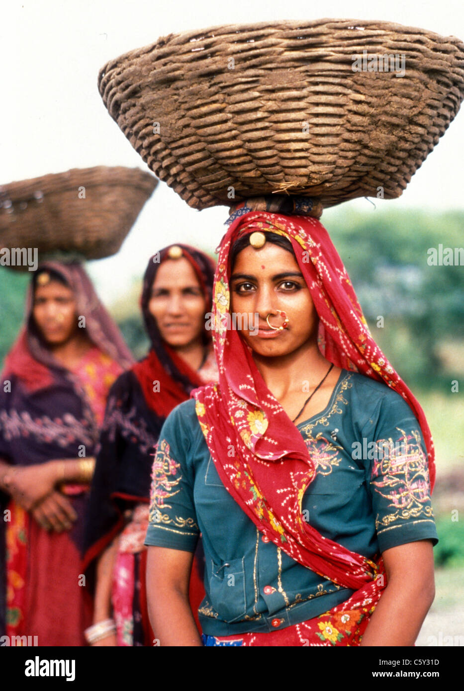Three Hindu women workers with baskets of chillis on their heads Orissa state India now called Odisha, 1984 Stock Photo