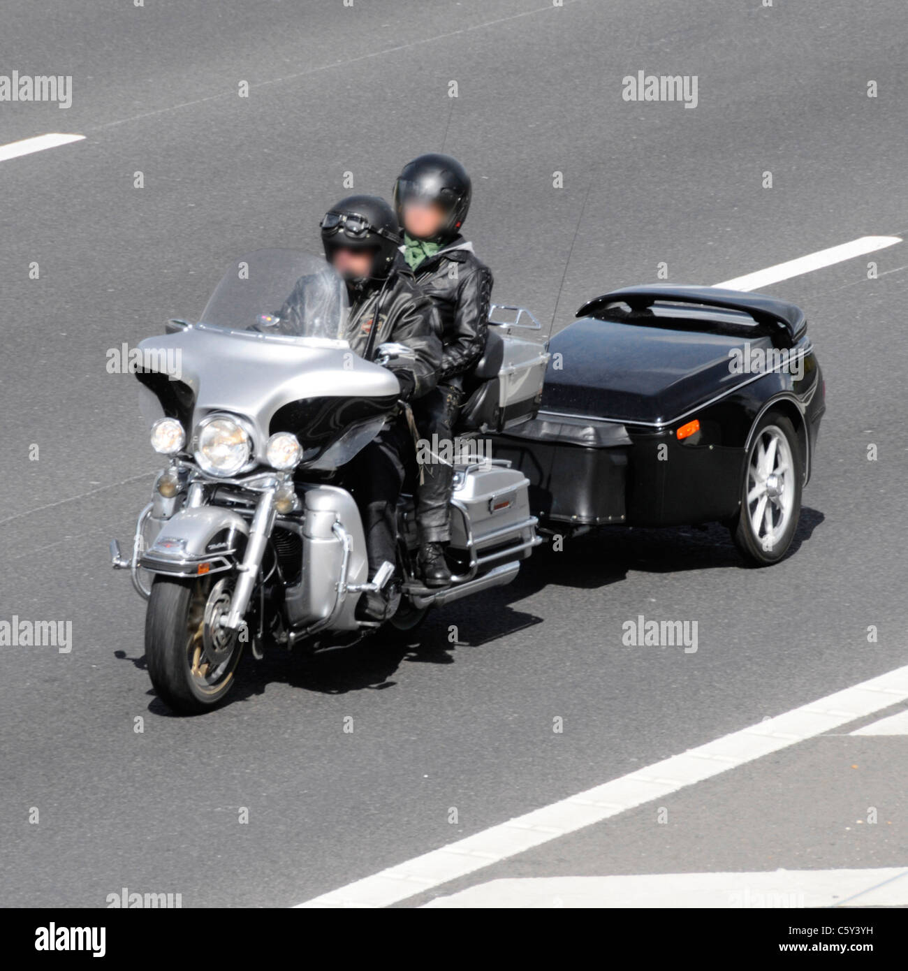 Male motorbike rider and woman pillion passenger wearing crash helmets