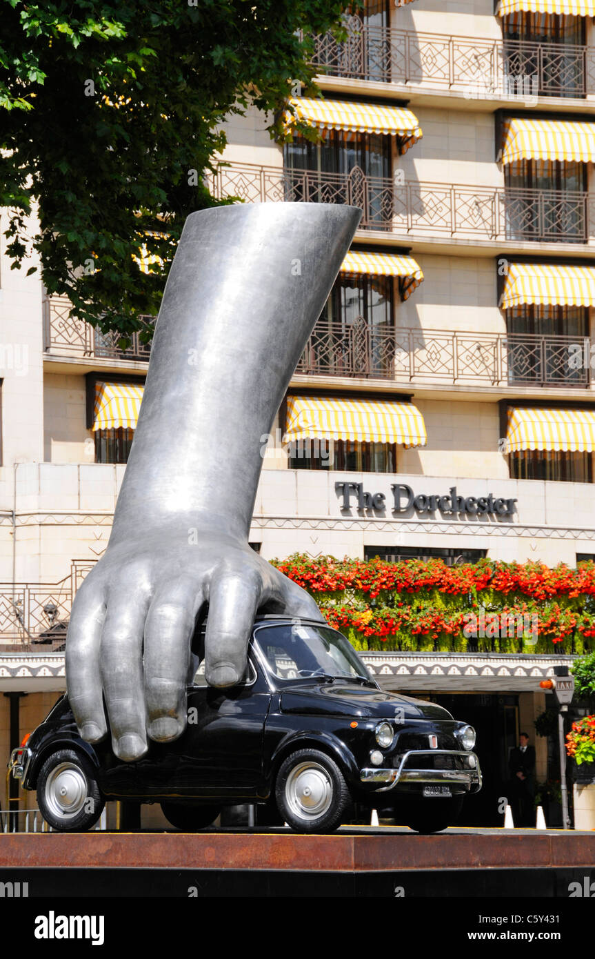 Hand on Vintage Fiat car in modern art sculpture 'Vroom Vroom' by Italian artist Lorenzo Quinn outside Dorchester Hotel in Mayfair London UK Stock Photo