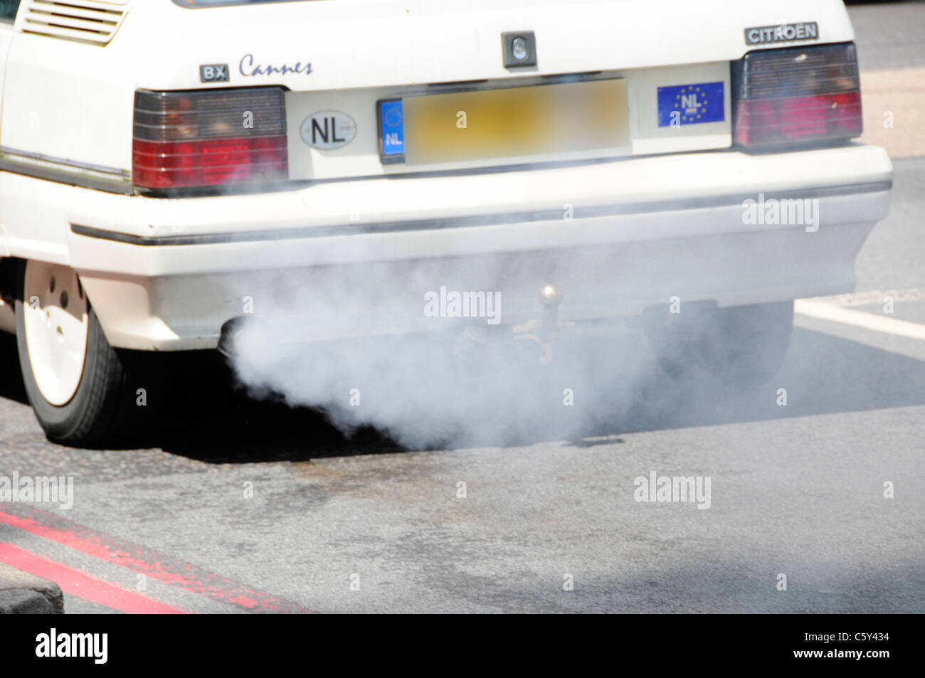 Dutch registered old Citroen car with defective polluting exhaust system fumes damaging environment driving on road London UK (obscured number plate) Stock Photo