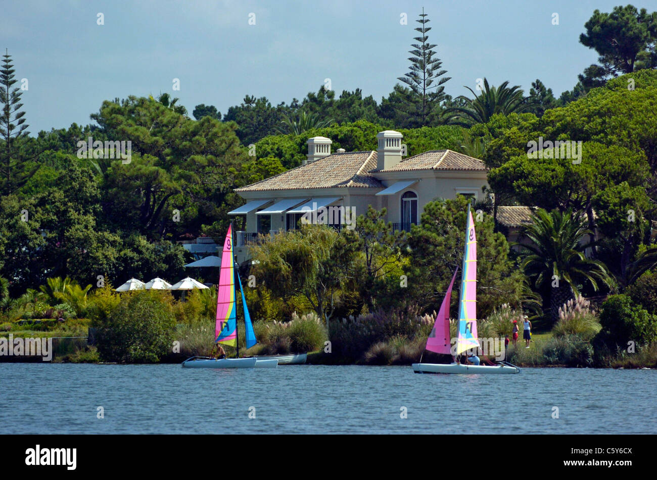 Sailing in front of the lakeside homes in the upmarket area of  Quinta do Lago area of the Algarve, Portugal. Stock Photo
