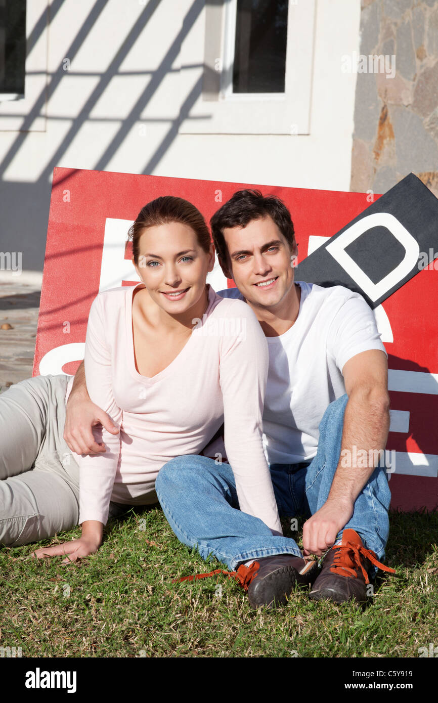 Portrait of happy young couple sitting in front of their new home Stock ...