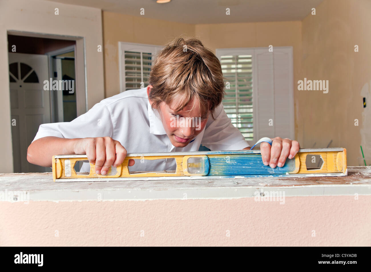 11 year years old caucasian boy checks horizontal level of pony wall during kitchen remodeling. MR © Myrleen Pearson Stock Photo