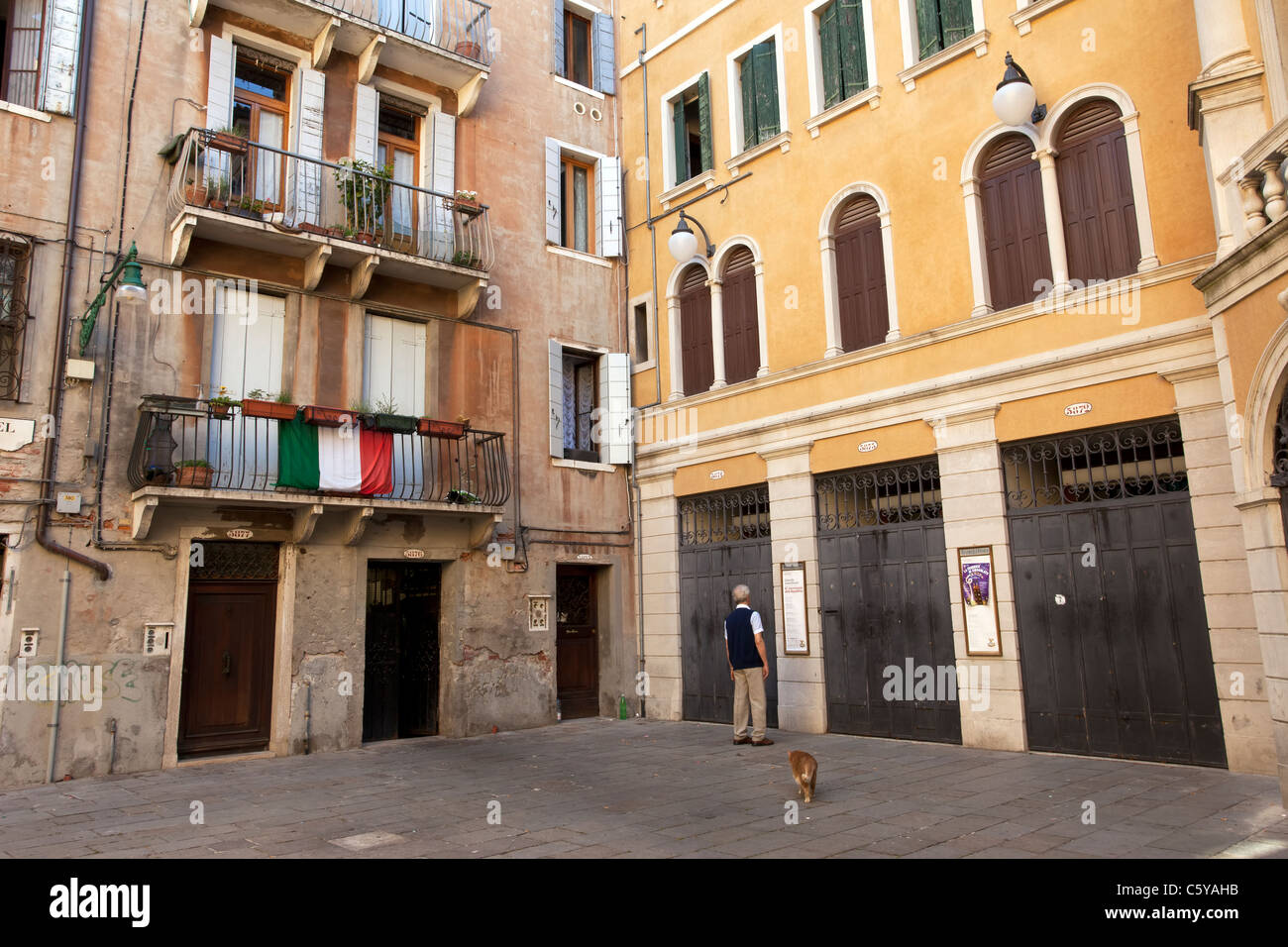 A man entering his house in Venice, Italy with his dog.  Shows ancient architecture of the buildings. Stock Photo