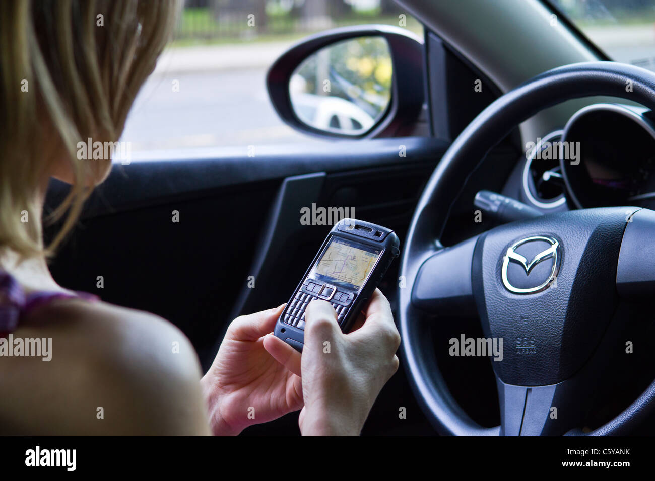 Woman in car using phone GPS to find driving directions Stock Photo