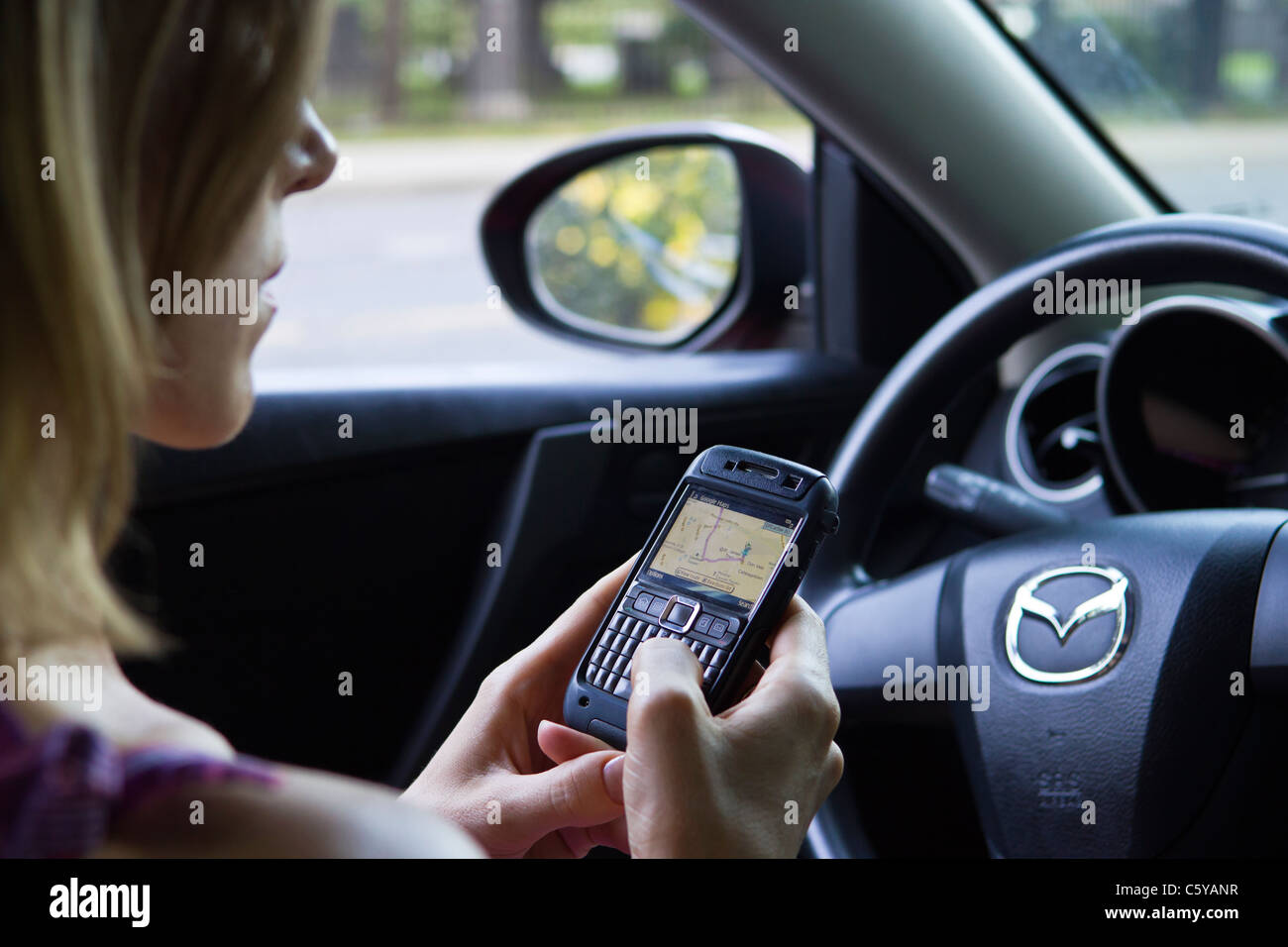 Woman in car using phone GPS to find driving directions Stock Photo