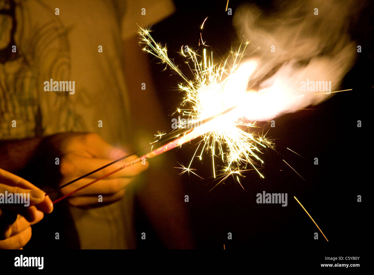 Two People Lighting Each Others Sparklers At Night Stock Photo