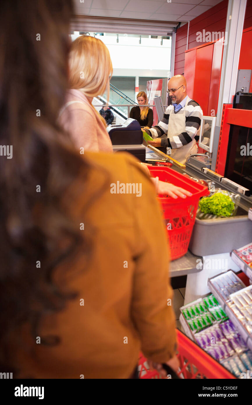 Shop assistant with customers in supermarket Stock Photo