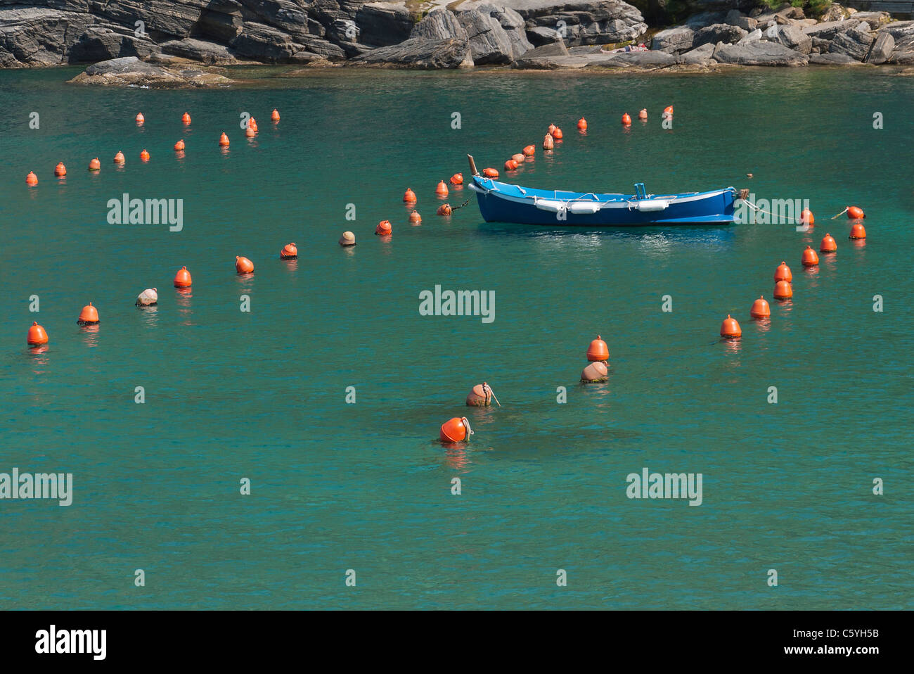 Row boat moored in harbor surrounded by small orange markers (buoys or bumpers), Vernazza, Cinque Terre, Italy. Stock Photo