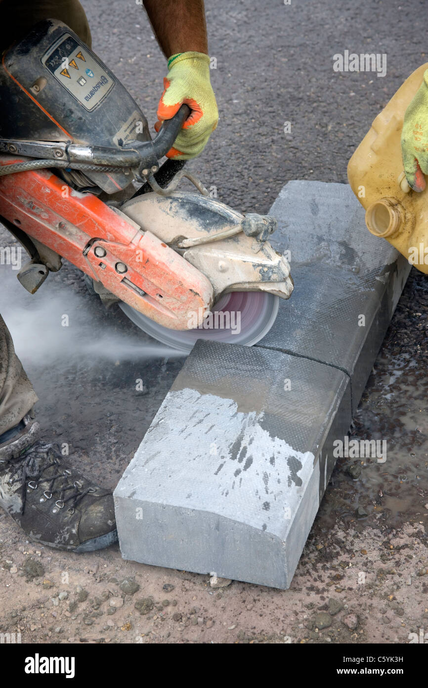 Workmen cutting a kerbstone (curbstone )with a diamond tipped cutting