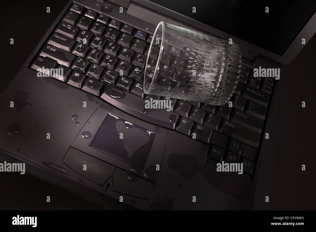 A glass of water accidentally spills on the keyboard of the laptop