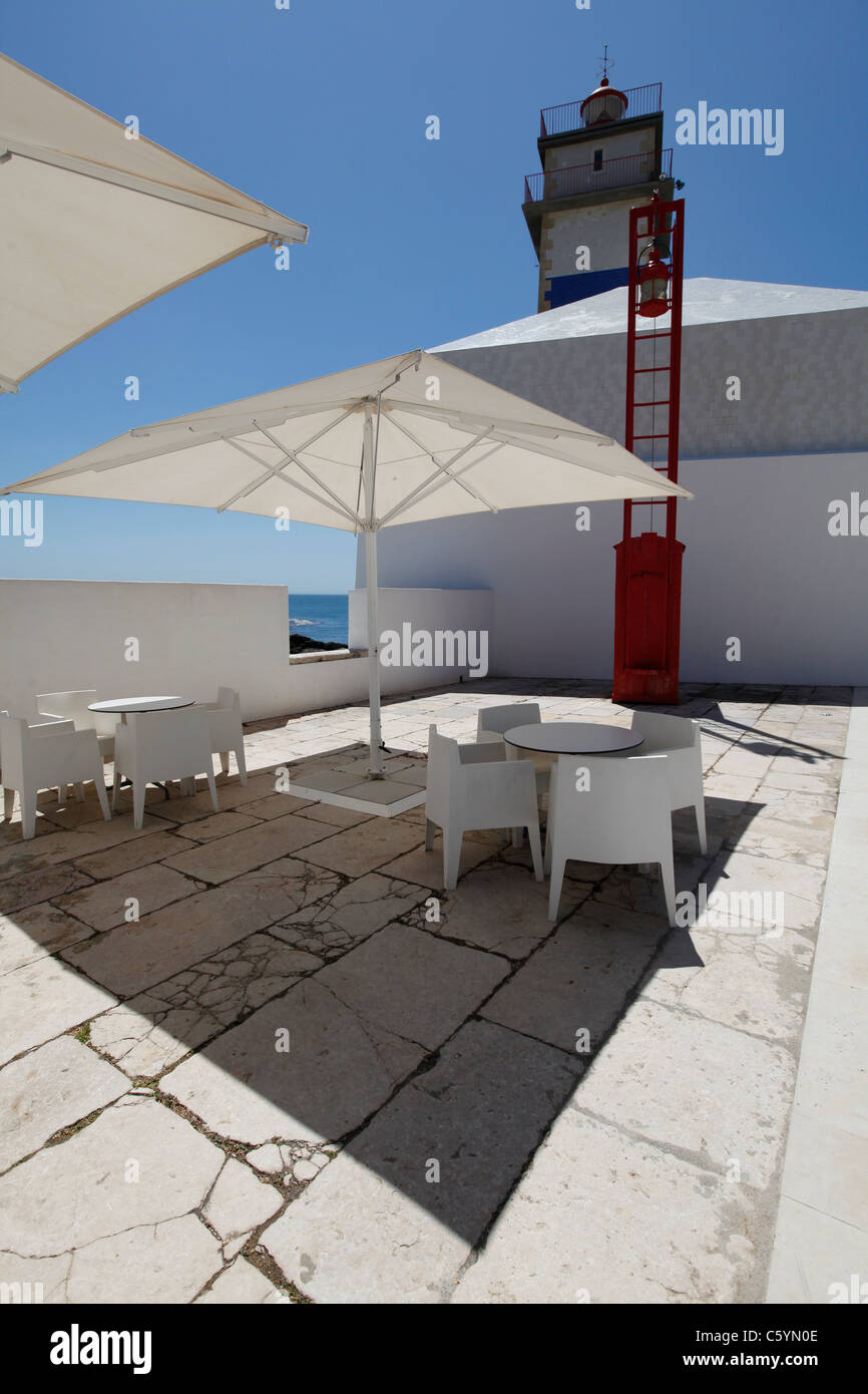 Inside Santa Marta Lighthouse (in the background) patio, with comfortable looking white chairs and parasol. Stock Photo