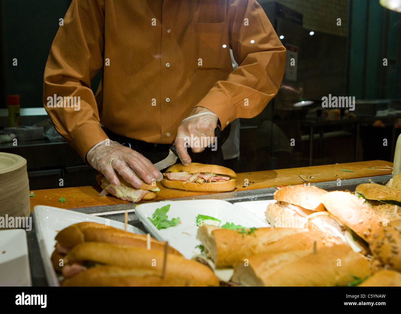 Cook preparing sandwiches behind cafeteria counter Stock Photo