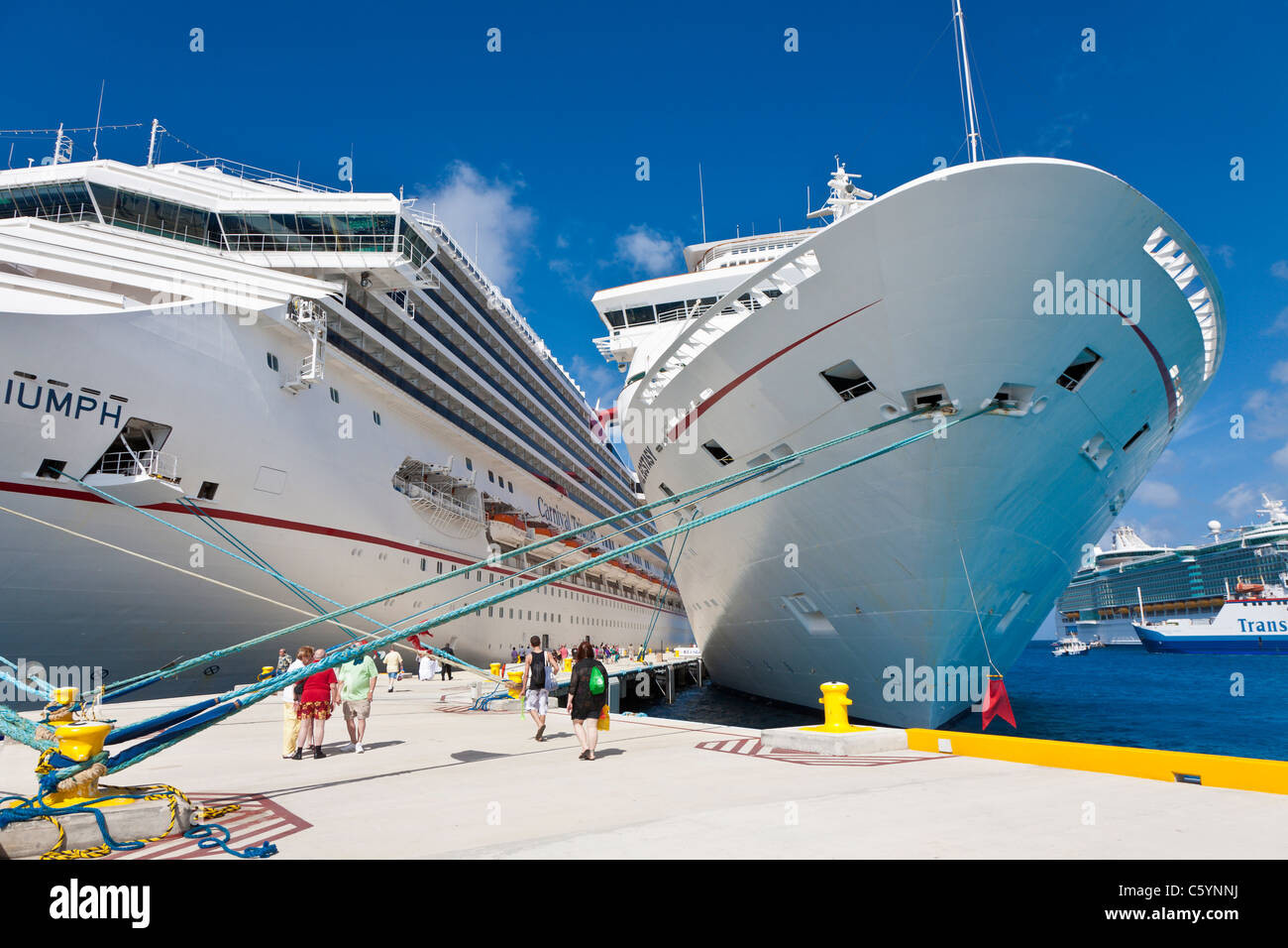Cruise ship passengers on pier near Carnival cruise ships Triumph and Ecstasy in Cozumel, Mexico in the Caribbean Sea Stock Photo