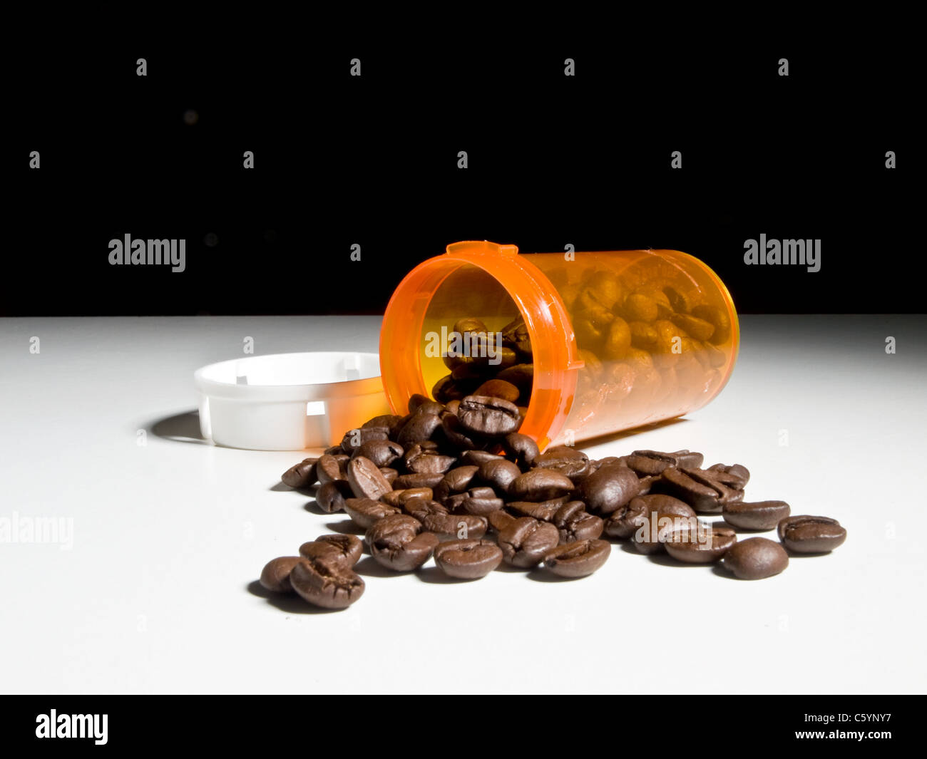 Coffee beans spill from a prescription drug container. Concept Rx
