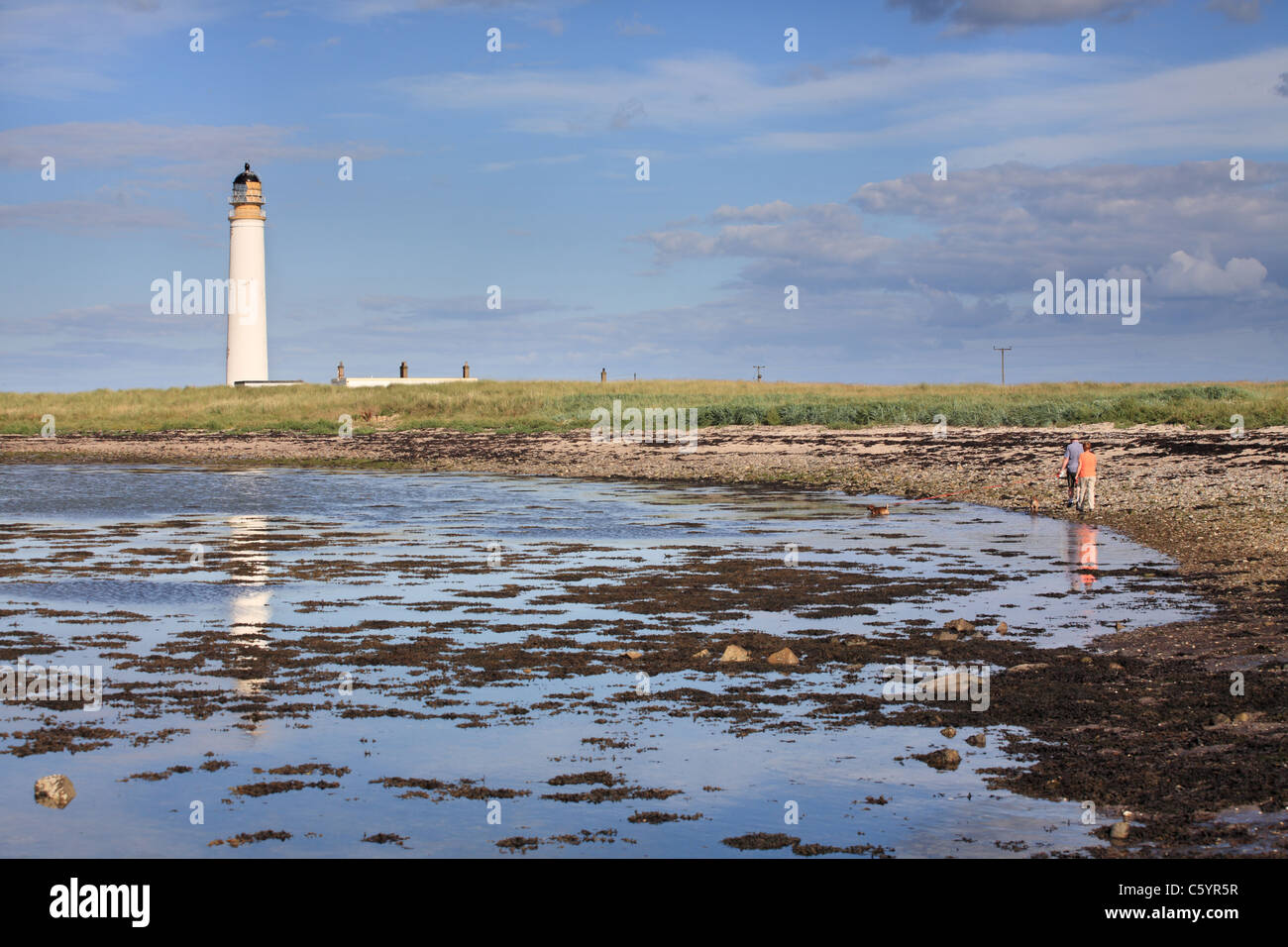 Couple with dog walking by Barns Ness Lighthouse, near Dunbar, East Lothian, Scotland, UK Stock Photo