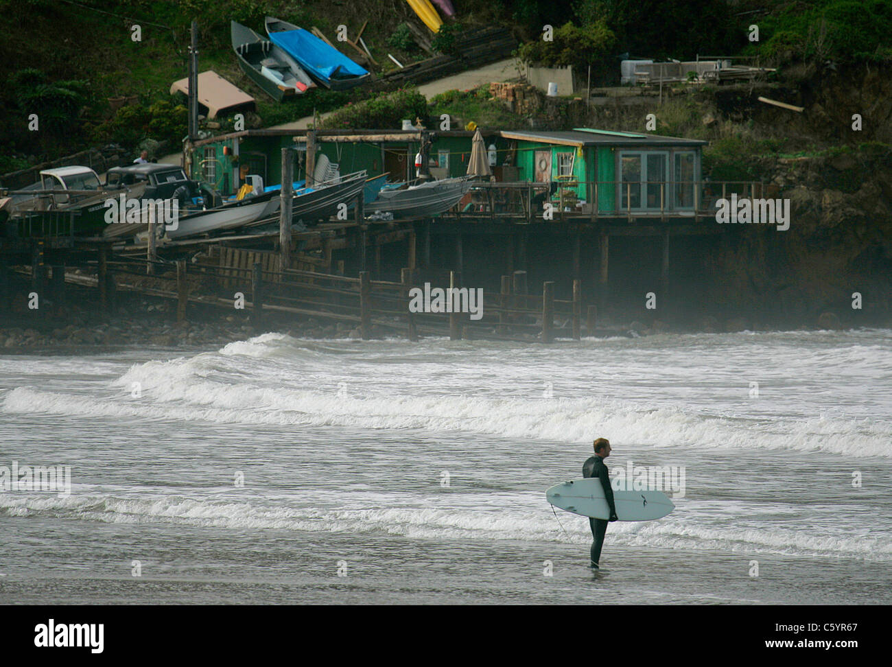Surfer watches waves from California beach Stock Photo