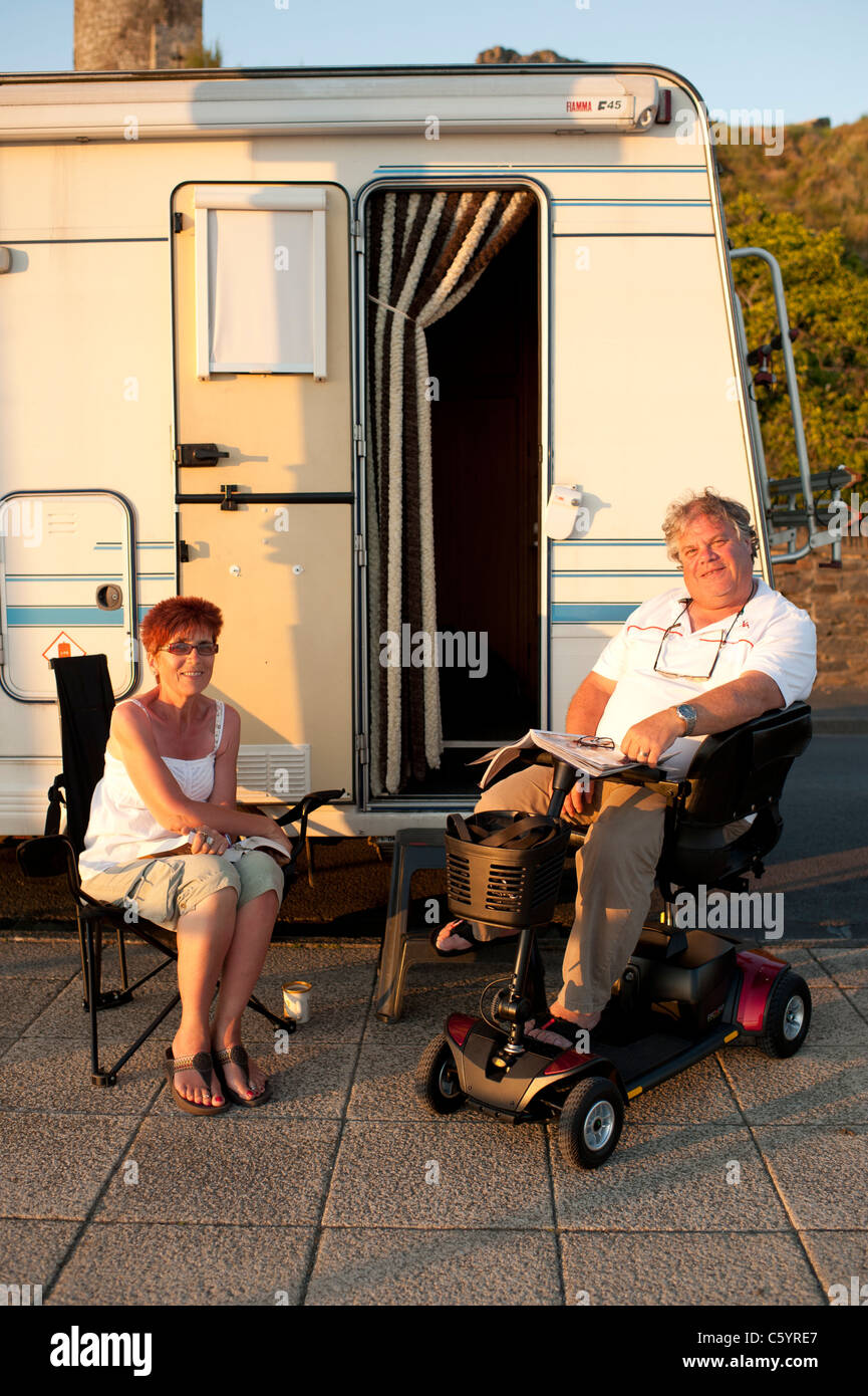 a middle aged couple [disabled husband] on holiday sitting outside their mobile home campervan, Aberystwyth Wales UK Stock Photo