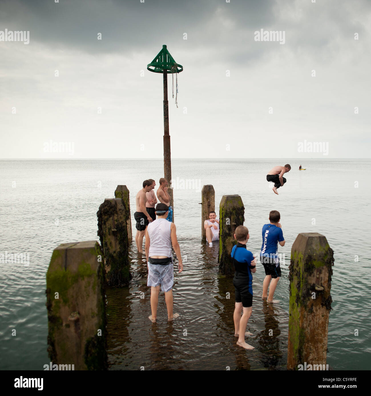 Summer afternoon, a group of Teenagers playing on the wooden jetty , Aberystwyth wales uk Stock Photo