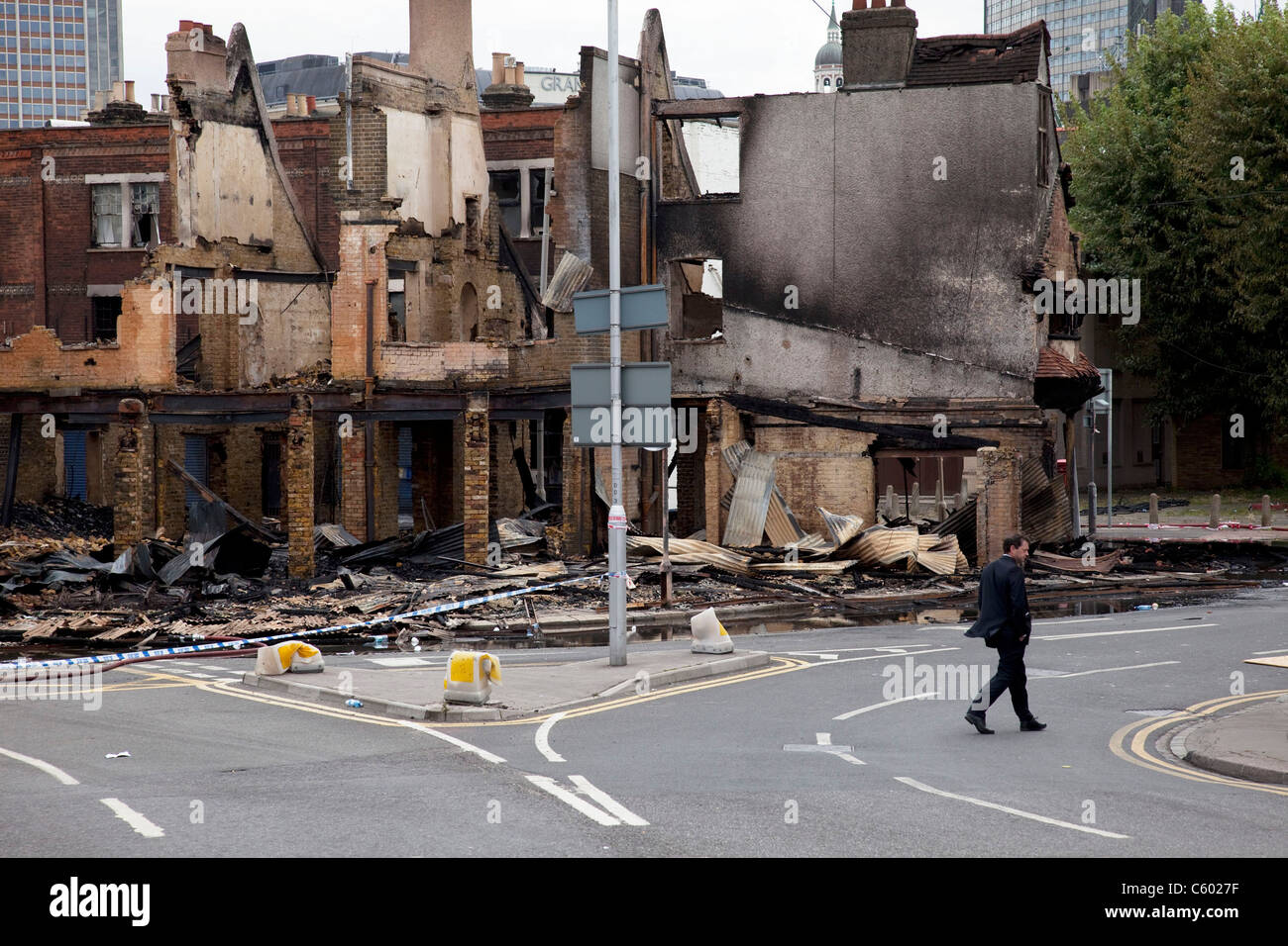 Man passes the burnt out remains of two furniture businesses at Reeve ...