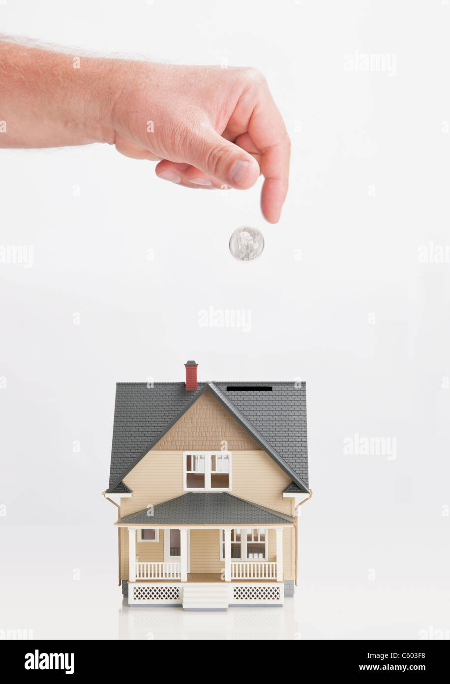 Close up of man's hand throwing coin into model house Stock Photo Alamy