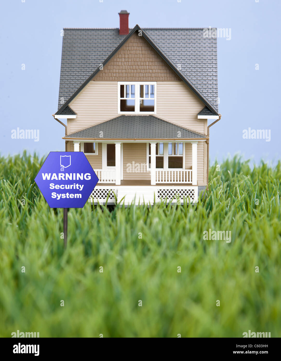 Model house on fake grass with warning security sign Stock Photo