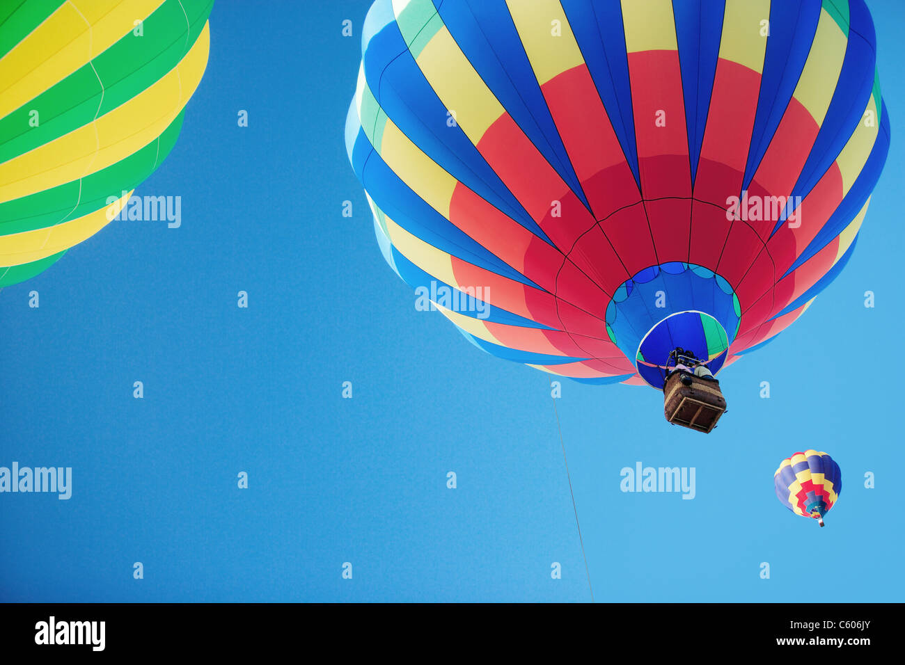 Three hot air balloons rising into a blue sky Stock Photo