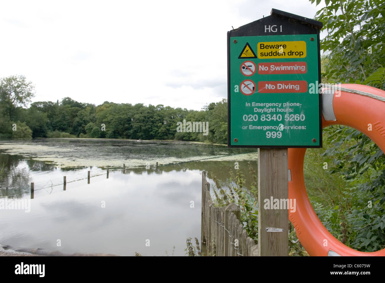 London Parliament Hill Hampstead Heath Highgate no. 1 pond with warning notice beware sudden drop no swimming no diving safety ring emergency number Stock Photo