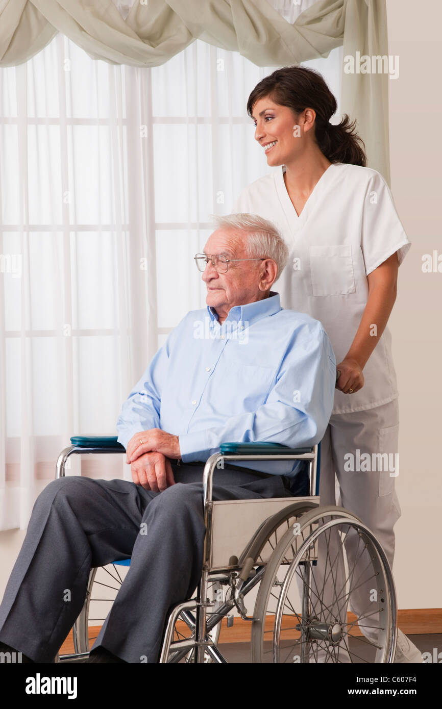 Female nurse pushing her patient on a wheelchair Stock Photo - Alamy