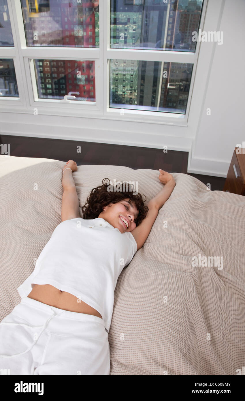 USA, New York City, woman stretching on bed Stock Photo