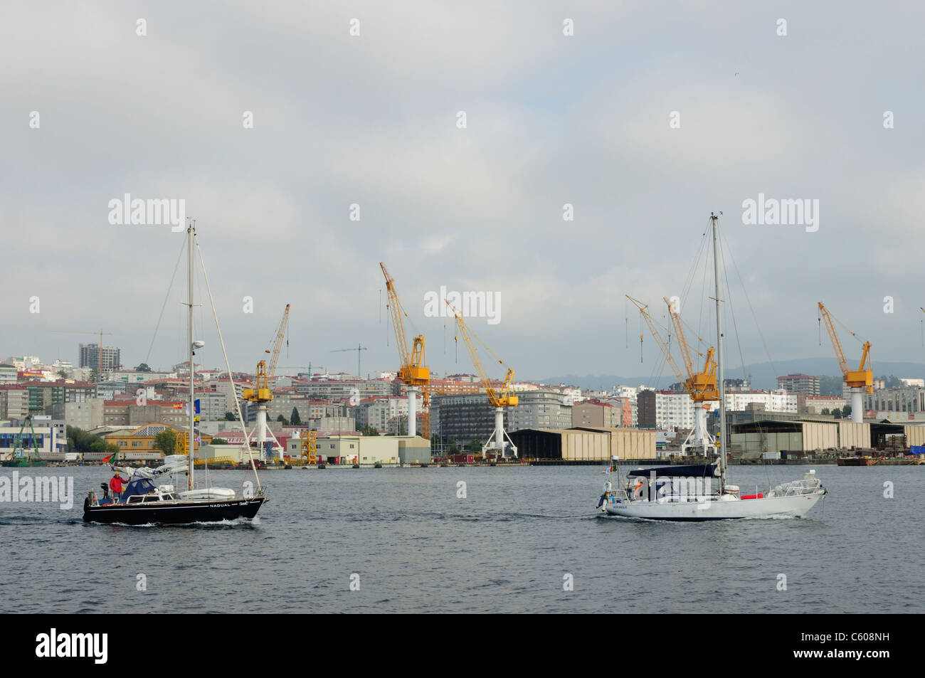 Sailboats sailing in front of the shipyards. Vigo, Spain Stock Photo