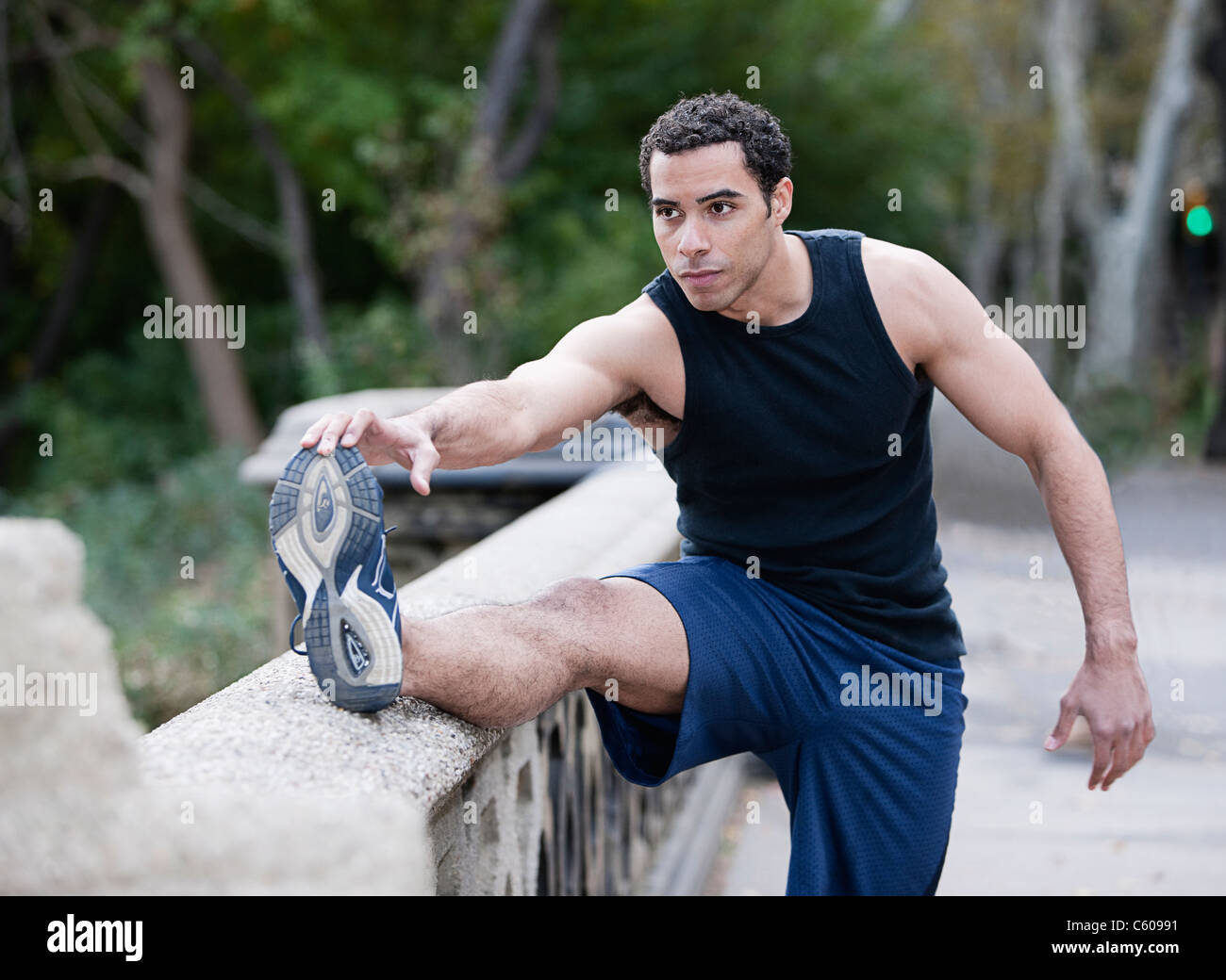 USA, New York, New York City, Young man stretching legs in park Stock Photo