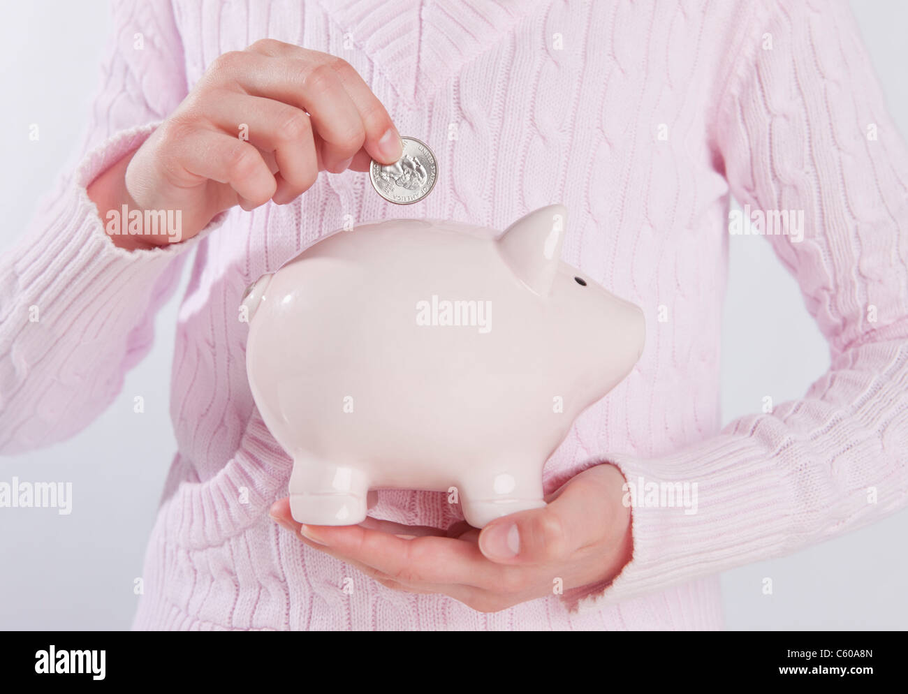 Girl putting a coin into a piggy bank Stock Photo - Alamy