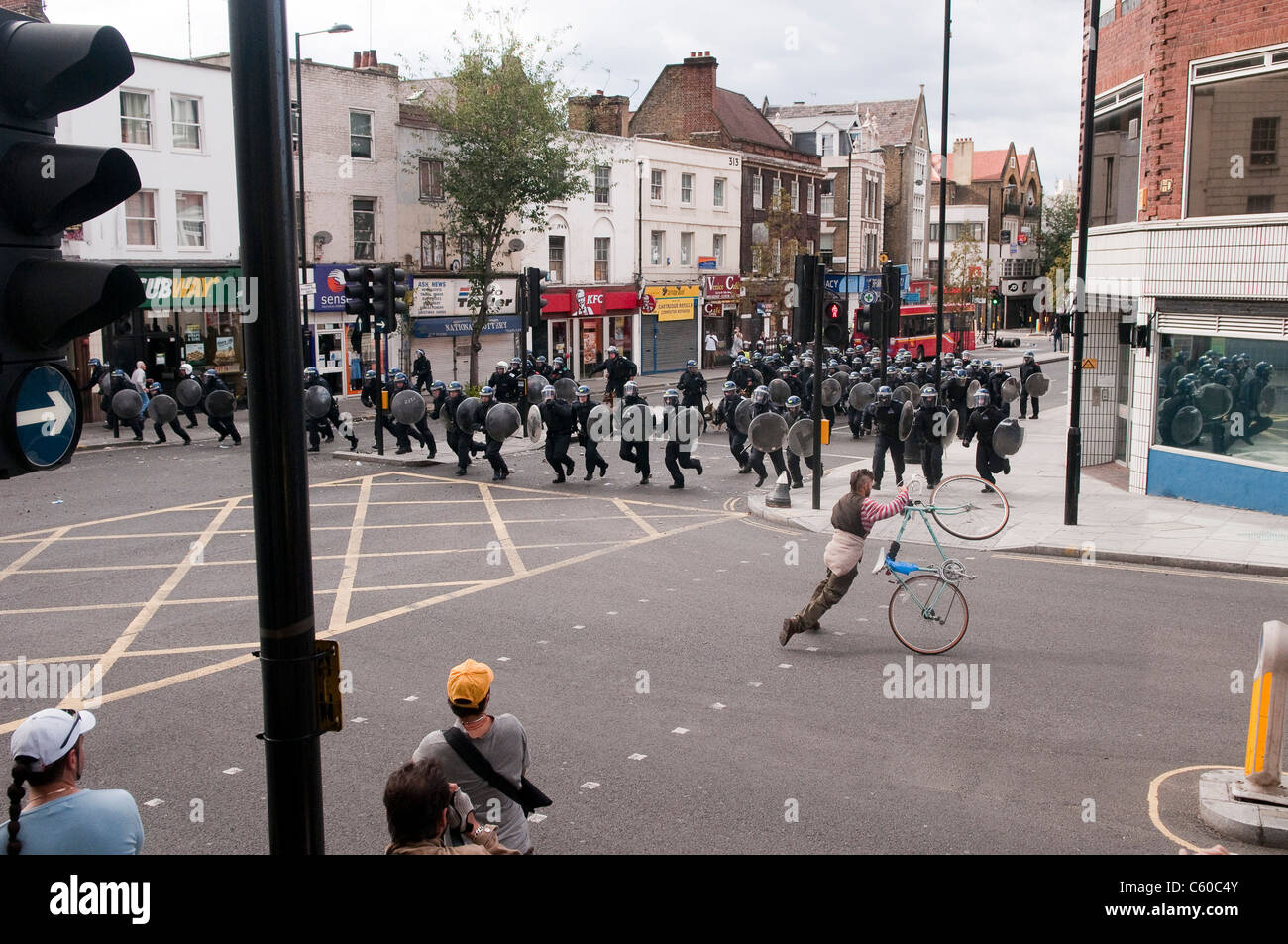 Man with a bicycle getting out of the way of riot police running down Mare Street, London Riots - Hackney Central - 8/8/2011 Stock Photo