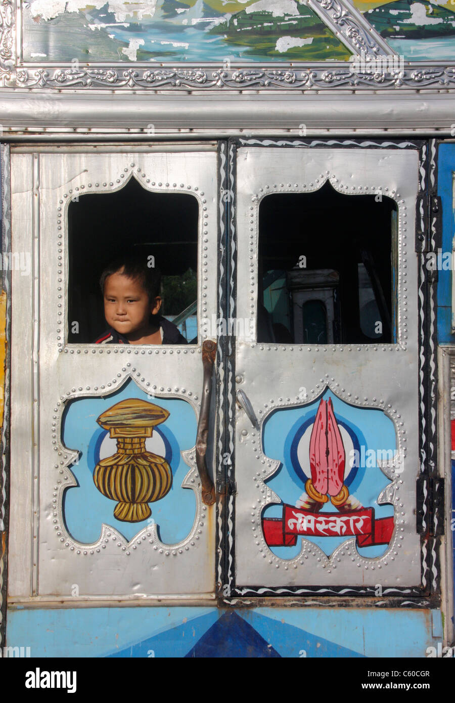 Small child peers from locally crafted ornate window of a Nepali Tata truck Butwal Nepal Stock Photo