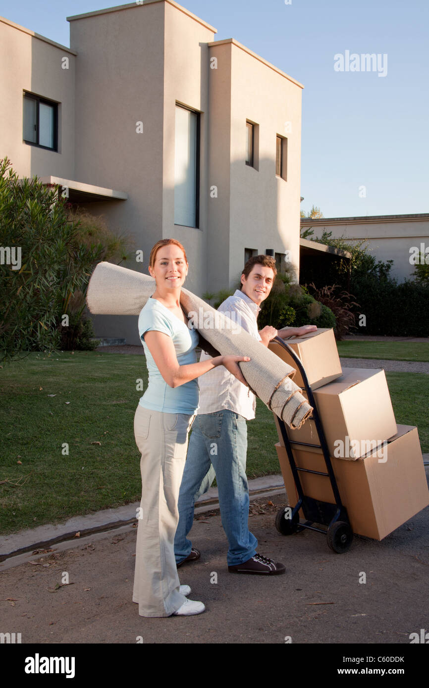 Portrait of a happy couple with moving boxes and small rug Stock Photo