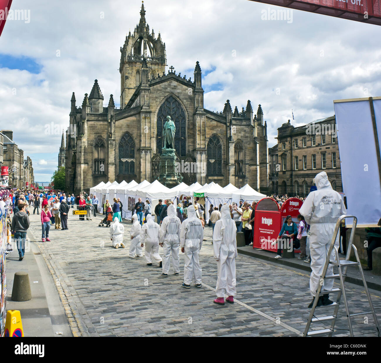 The West entrance to the Royal Mile Edinburgh Fringe Festival area with displays tents and shows with St. Giles Cathedral behind Stock Photo