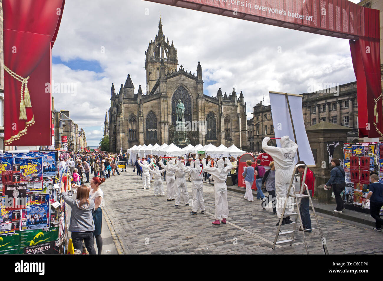 The West entrance to the Royal Mile Edinburgh Fringe Festival area with displays tents and shows with St. Giles Cathedral behind Stock Photo