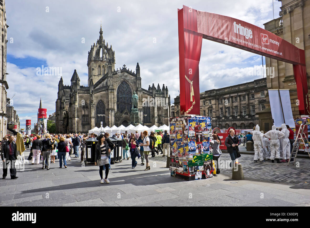 The West entrance to the Royal Mile Edinburgh Fringe Festival area with displays tents and shows with St. Giles Cathedral behind Stock Photo