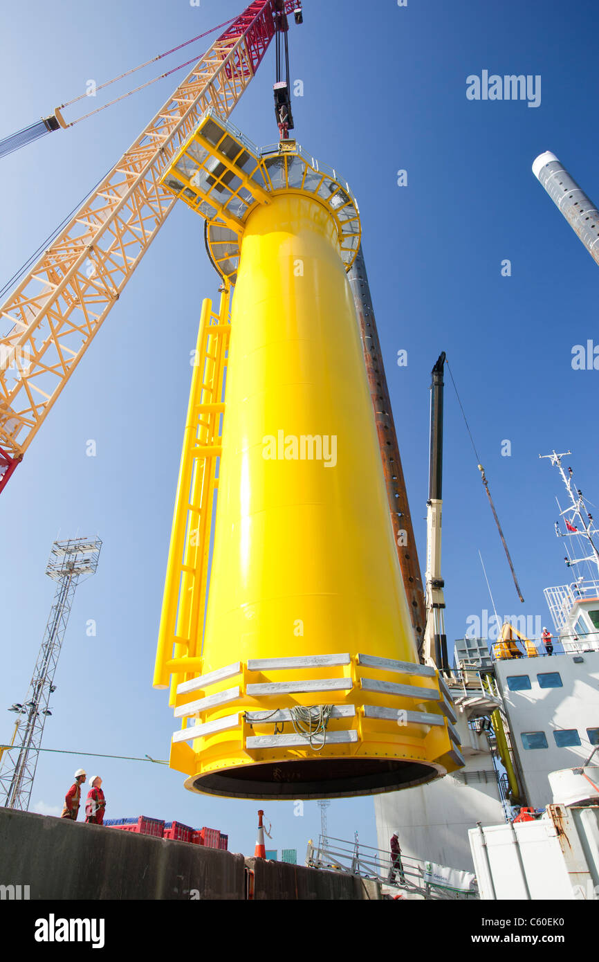 A crane lifts a transition piece of a wind turbine onto a jack up barge