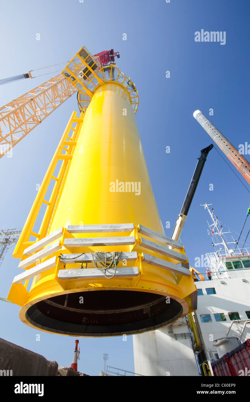 A crane lifts a transition piece of a wind turbine onto a jack up barge