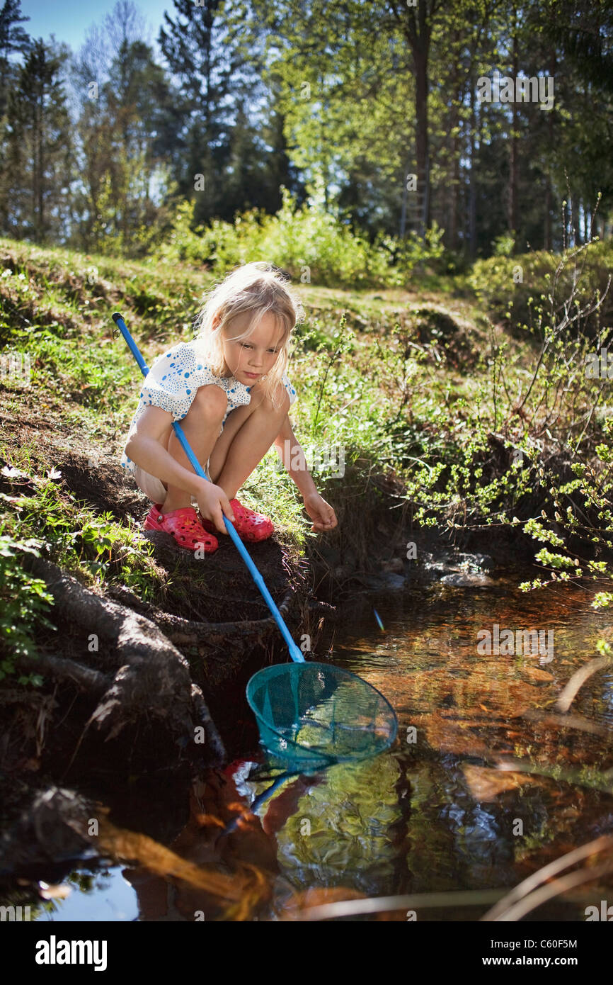 Girl fishing with net in creek Stock Photo